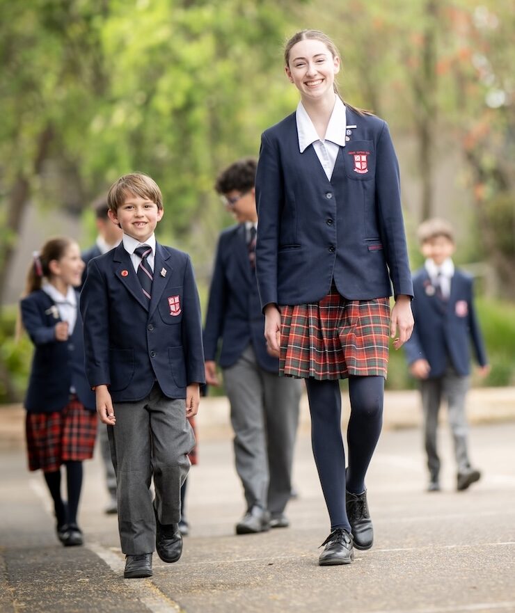 Female senior Northholm Grammar student walking with a male junior student outdoors and other students following in the background